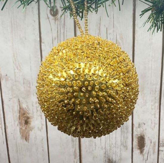 Add a touch of opulence to your holiday decor with our 5" Sequin Beaded Ball Ornament in Gold. This stunning ornament is beautifully embellished with shimmering sequins and beads, creating a radiant sparkle that catches the light perfectly.