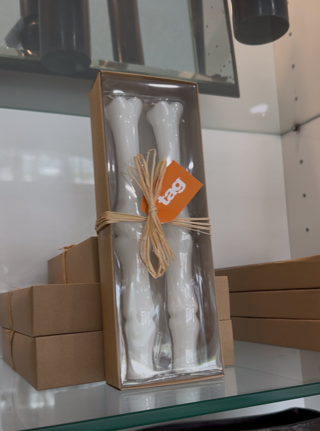 A set of two white bone-colored taper candles packaged in a clear box.