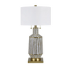 The Caldwell Table Lamp by Crestview Collection features a ceramic body of chalky gray ceramic intersected with metallic gold lines. Arranged in a geometric pattern the just position of the shiny lines gives the body a faceted appearance. It features plated brass components and a white linen shade.