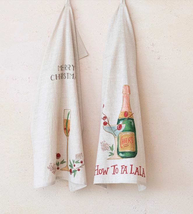 This set of two cotton slub printed tea towels features a festive and fun touch to the kitchen. The towels have a rectangle shape and a slub texture, giving them a casual and cozy feel. They come in two styles, each with a different holiday cocktail, saying, and loop in multicolor, with sayings like "Merry Christmas" and "How to Falala".