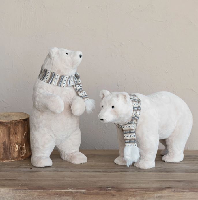 This faux fur upright polar bear is a charming and adorable decorative item that can brighten up the space. It features a smooth, shiny body with cream color and black details, along with a pair of ears, a black nose, and two black eyes. The scarf is red and white with a striped pattern.