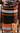 Plaid blanket with black, orange, and gray pattern rolled up and tied with twine.
