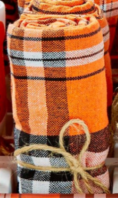 Plaid blanket with orange, black, and white pattern on a wooden surface