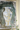 Decorative wall art with a white vase with gold patterns on a textured gray background
