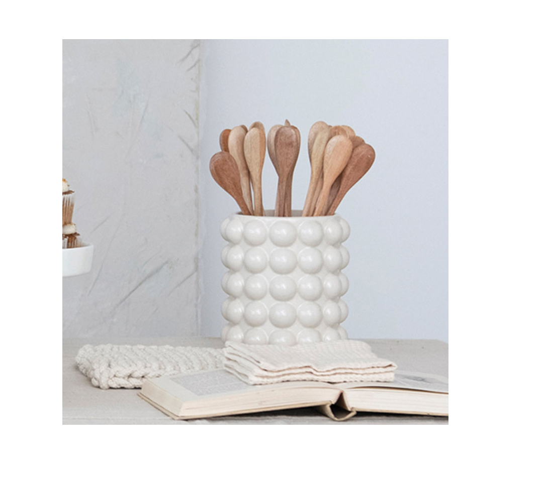 A beige stoneware canister with raised dot patterns and an acacia wood lid.