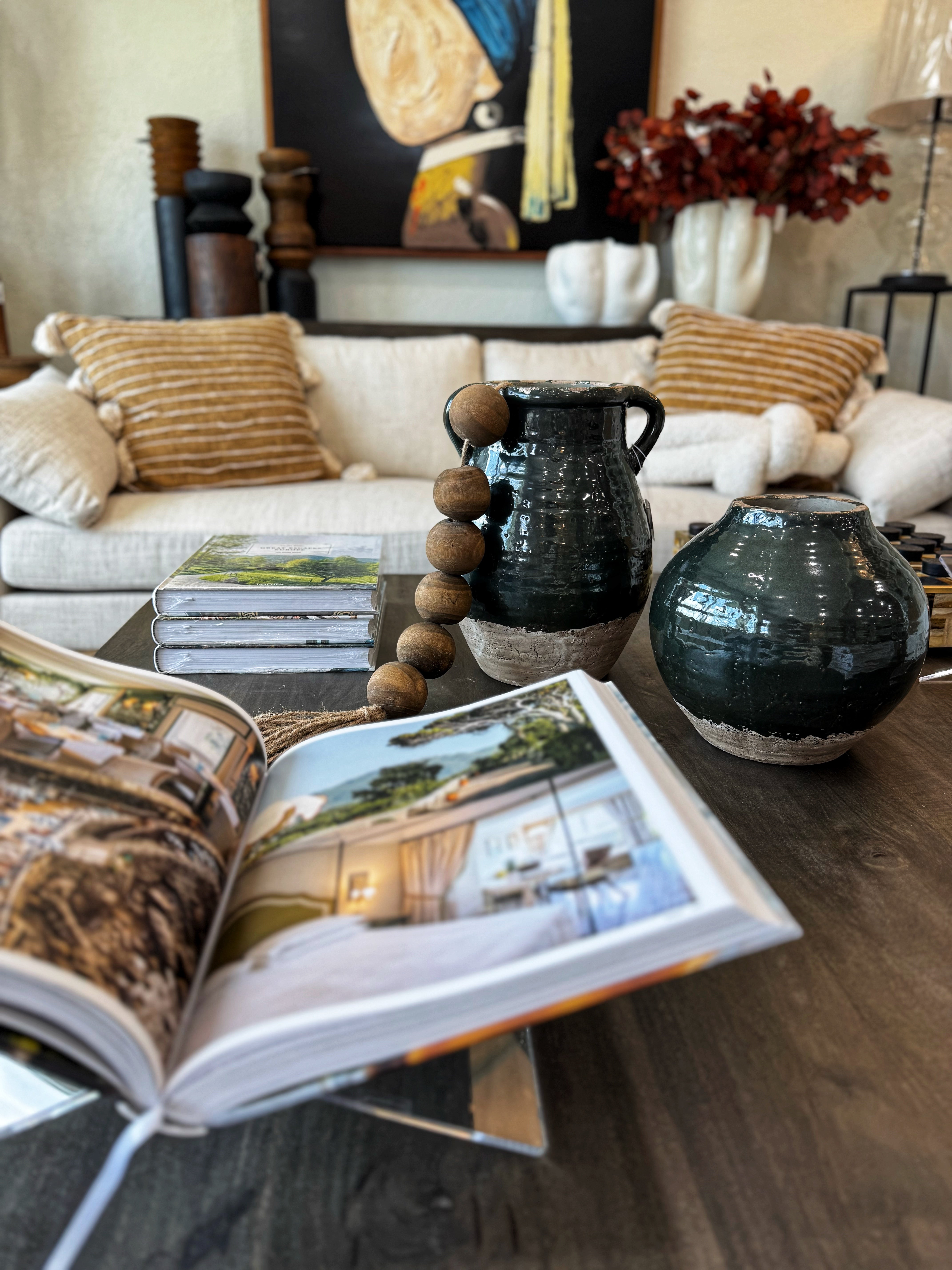 Open magazine on a coffee table with decorative vases and books in a living room setting.