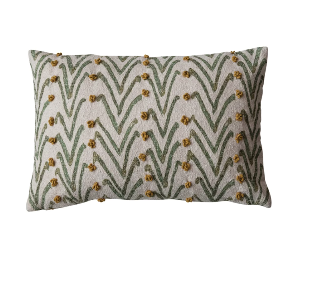 A woven cotton blend lumbar pillow with a geometric floral pattern in natural, green, and mustard colors, featuring French knots.