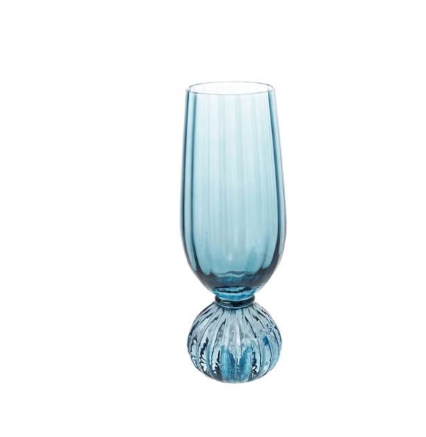 A blue pleated footed champagne glass against a white background.