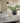 Bathroom with marble countertop, black vase with greenery, and wall-mounted mirror.