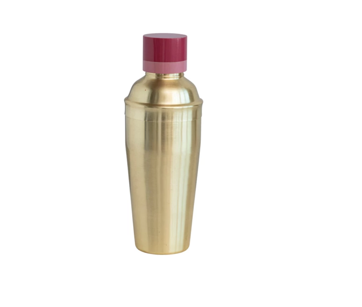 A gold stainless steel cocktail shaker with a two-tone red and beige resin lid.
