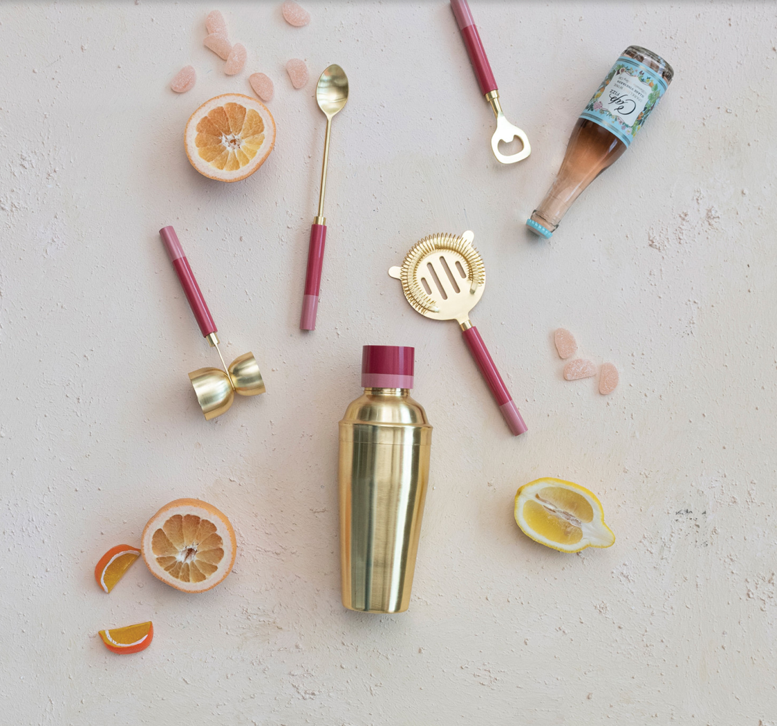 A gold stainless steel cocktail shaker with a two-tone red and beige resin lid.