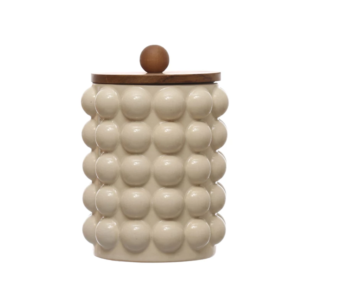 A beige stoneware canister with raised dot patterns and an acacia wood lid.