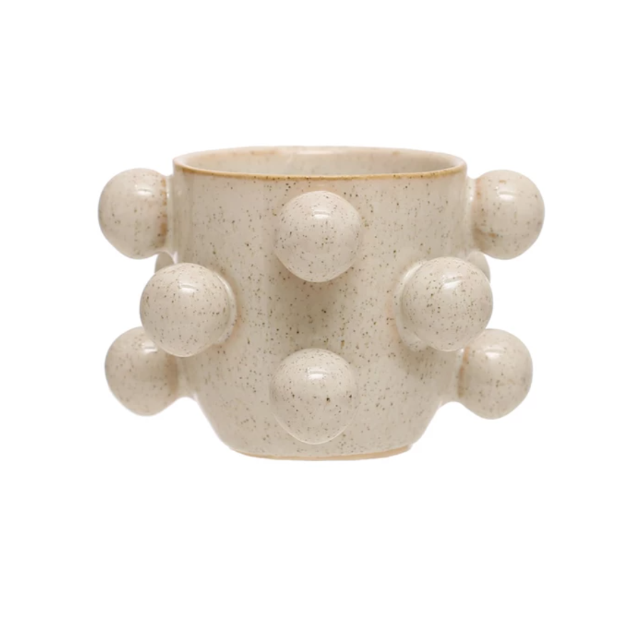A round stoneware planter with speckled cream color and reactive glaze, featuring multiple orbs on the side.