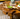 Wooden coffee table with a natural, rustic design, featuring a leaf-shaped dish with green apples on a textured surface.