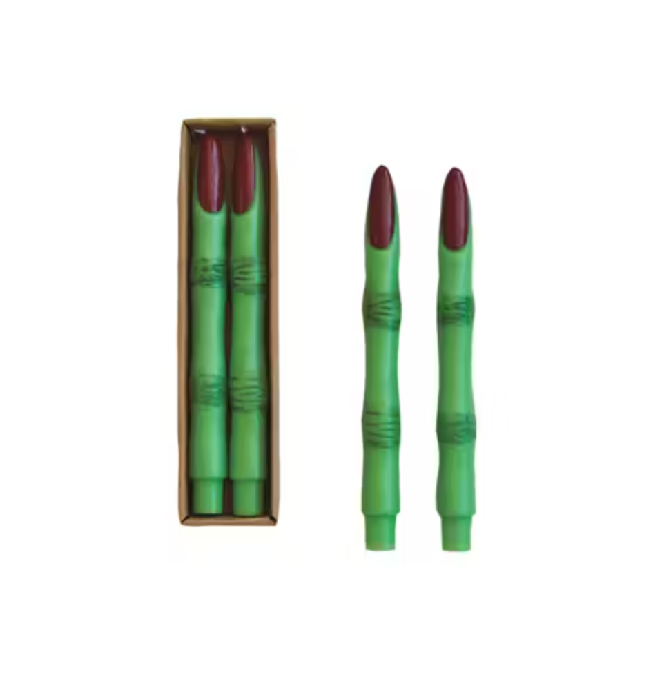 A set of two green unscented witch finger taper candles placed next to their open box.