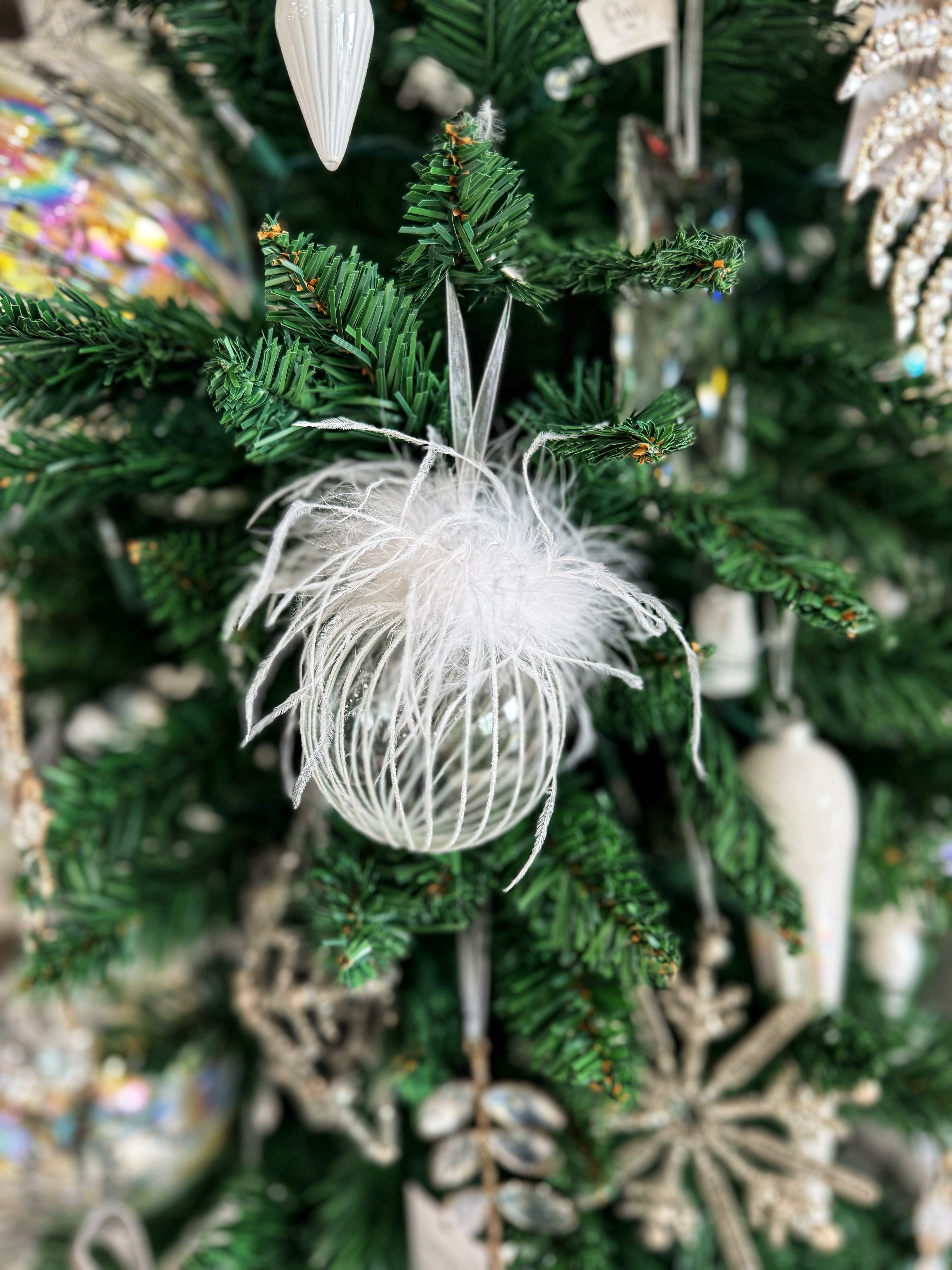 This exquisite ornament combines the elegance of glass with soft feathers, creating a stunning visual piece that catches the light beautifully. The clear and white color palette adds a touch of sophistication, making it perfect for both traditional and modern decor styles. Ideal for hanging on your Christmas tree or incorporating into seasonal displays, this ornament brings a unique and whimsical charm to your festive celebrations!